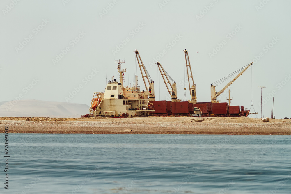 Cranes with boat and containers on the coasts of Paracas, Peru Cranes with boat and containers on the coasts of Paracas, Peru