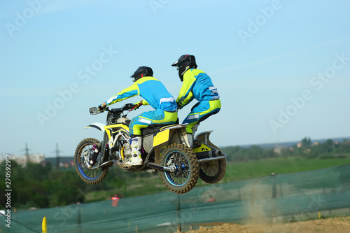 Fototapeta Naklejka Na Ścianę i Meble -  Sidecar motocross athletes jumping on the dirt track 