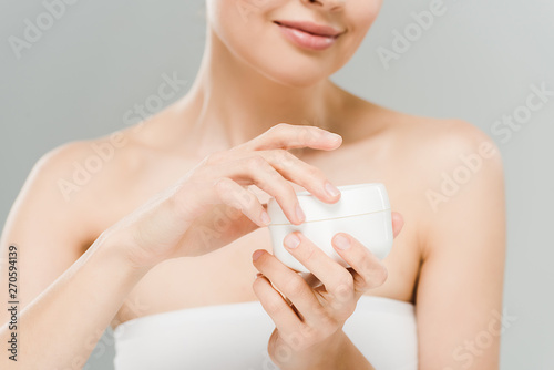 selective focus of woman holding container with face cream isolated on grey