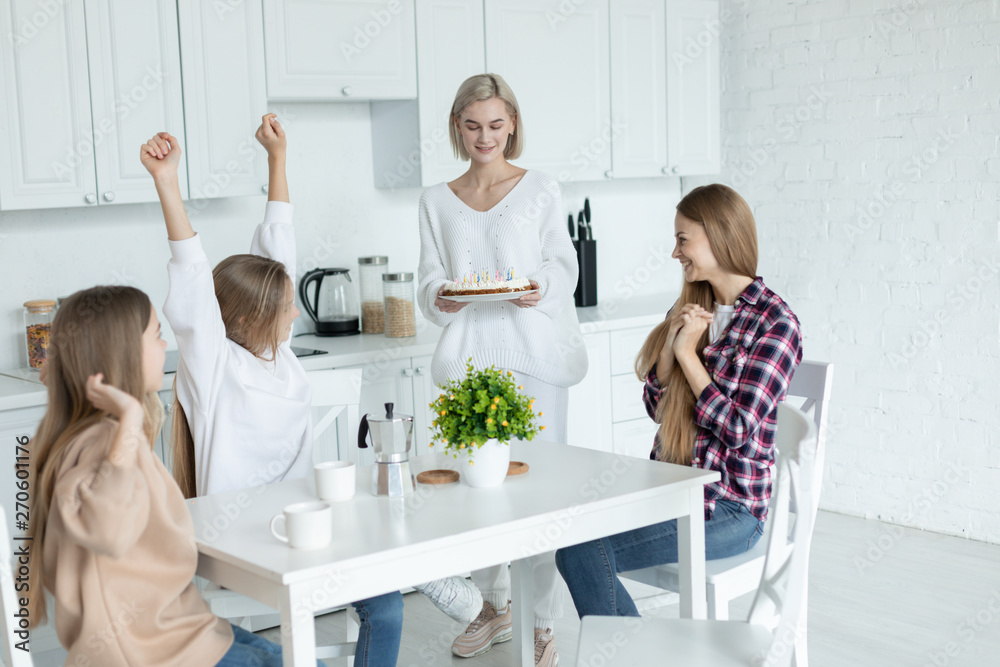 Happy young lesbian family celebrating birthday of their daughter in the kitchen at home Happy young lesbian family celebrating birthday of their daughter in the kitchen at home