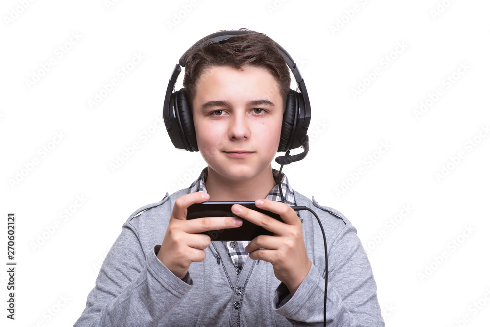 Schoolboy guy teenager with headphones playing a game on mobile phone. Gambling, telephone addiction Schoolboy guy teenager with headphones playing a game on mobile phone. Gambling, telephone addiction