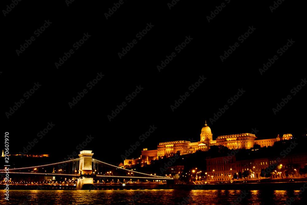 night Budapest, glowing in gold. The bridge chain over the Danube is illuminated by light bulbs. photo from the river night Budapest, glowing in gold. The bridge chain over the Danube is illuminated by light bulbs. photo from the river