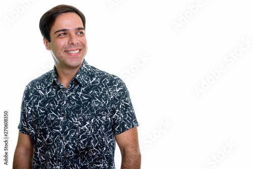 Studio shot of young happy Persian man smiling and thinking whil