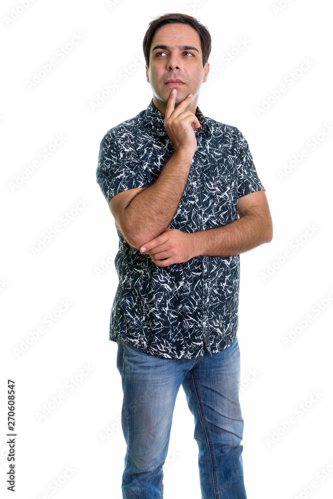 Studio shot of young Persian man standing while thinking isolate Studio shot of young Persian man standing while thinking isolate