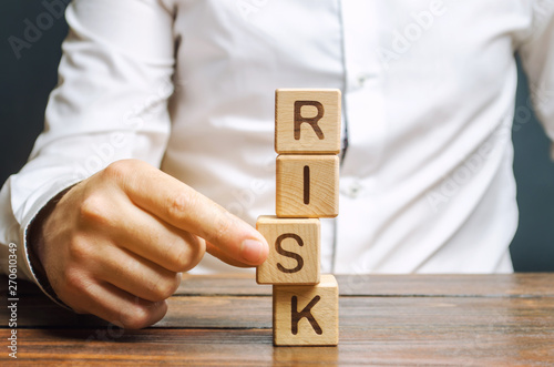 Man removes blocks with the word Risk. The concept of reducing possible risks. Insurance, stability support. Legal protection of business interests. Favorable investment climate. Financial pillow. photo