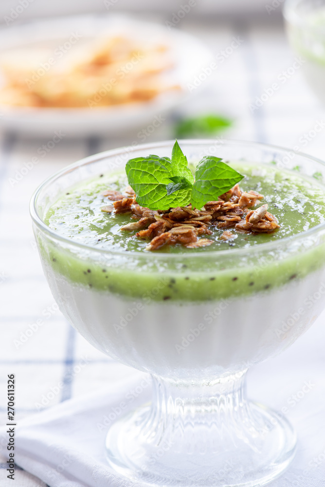 Milk dessert with kiwi. Pana cotta with green kiwi jelly in glass bowls. Sweet breakfast in bright colors. Milk dessert with kiwi. Pana cotta with green kiwi jelly in glass bowls. Sweet breakfast in bright colors.