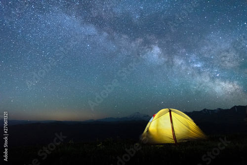 tourist tent of yellow color against the night sky with the Milky Way