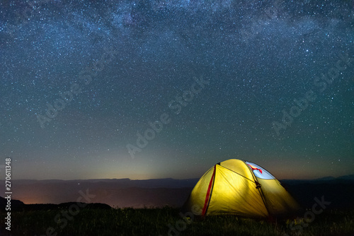 tourist tent of yellow color against the night sky with the Milky Way