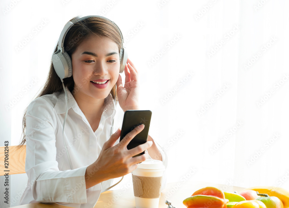 Beautiful young asian woman happy to use smartphone and listening music on headphone. Beautiful young asian woman happy to use smartphone and listening music on headphone.