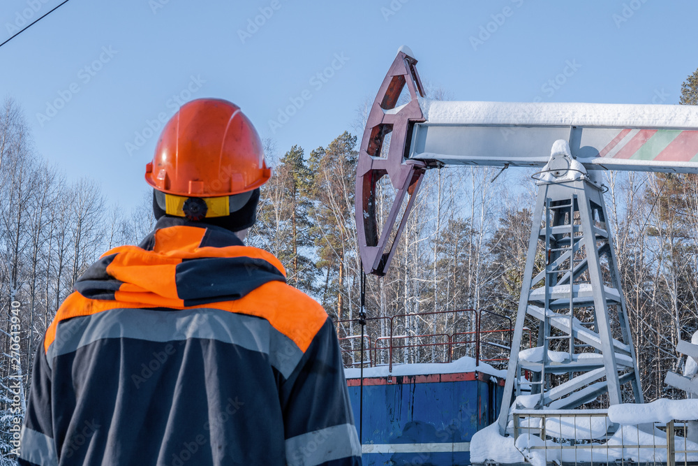 An image of oil worker at a pumpjack.Oil and gas industry. Silhouette oil pumps on a sunset sky background. Toned. An image of oil worker at a pumpjack.Oil and gas industry. Silhouette oil pumps on a sunset sky background. Toned.