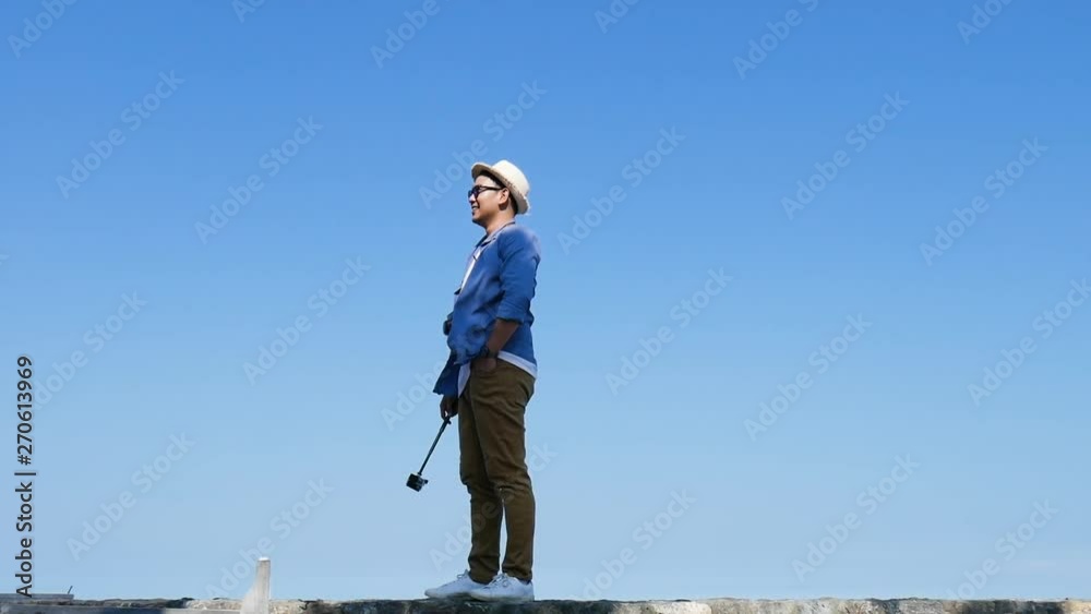 Happy tourist holding camera stick and looking around on the beach in sunny day. Happy tourist holding camera stick and looking around on the beach in sunny day.