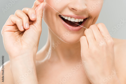 cropped view of happy naked woman flossing teeth with dental floss isolated on grey