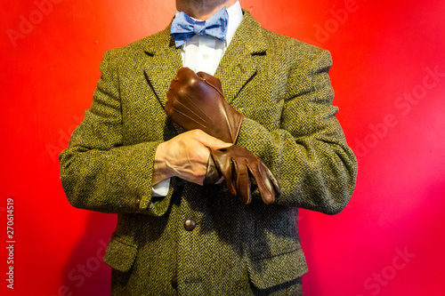 Portrait of Dapper Man in Tweed Suit Pulling on a Leather Glove. Strong Manly Determination in the Harsh Face of Cold Hands. Vintage Fashion and Style.