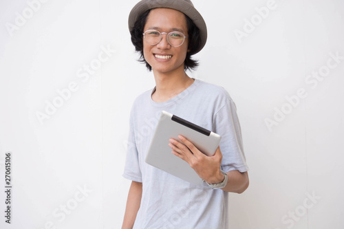 portrait of happy young asian man with fedora hat and glasses using tablet photo