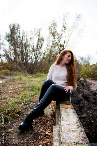 Portrait of young redhead woman sitting on a bench in autumn park photo