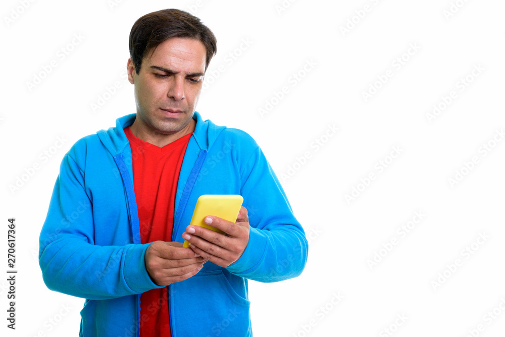 Studio shot of young Persian man using mobile phone isolated aga