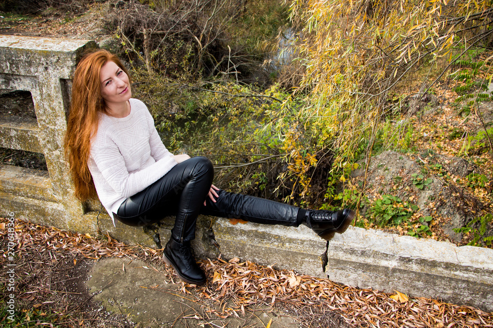 Portrait of young redhead woman sitting on a bench in autumn park Portrait of young redhead woman sitting on a bench in autumn park