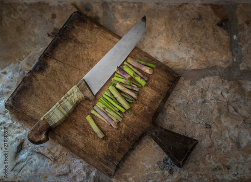Trozos de espárragos trigueros sobre una tabla de cortar junto a un cuchillo antiguo
