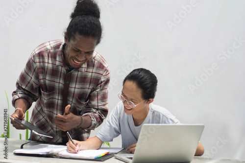 two friend with diffrent ethnic working together with laptop and tablet discussing something