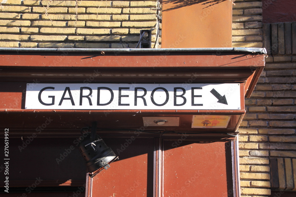 Sign on brick wall at a restaurant showing direction to the wardrobe (Dutch/German: Garderobe)