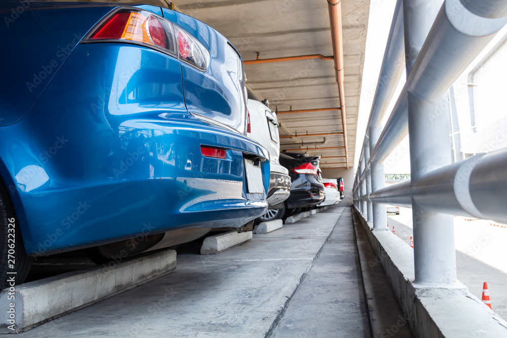 Naklejka premium Closeup blue cars parked in indoor parking building with steel rails, the concept of safety car.