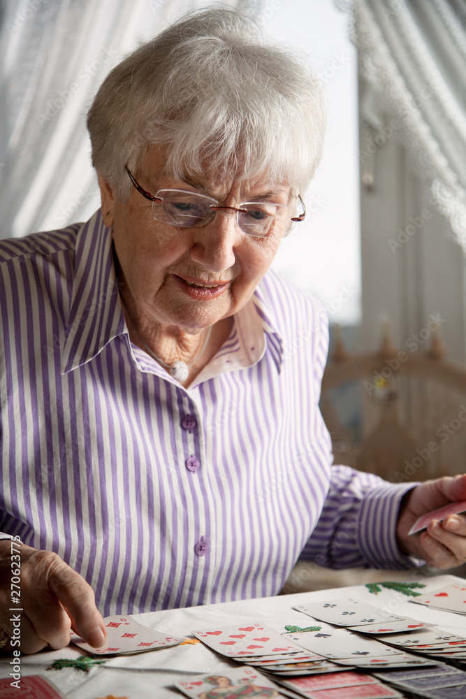 Senior lady playing solitaire cards at home Senior lady playing solitaire cards at home