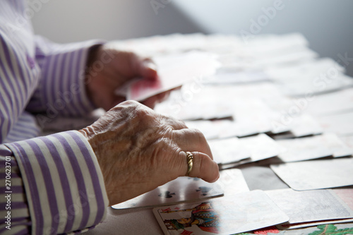 Fotografie Closeup of wrinkled hands of senior lady playing solitaire