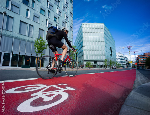 Bild auf Leinwand Cyclist in a symbol-marked, red bicycle lane in an urban area