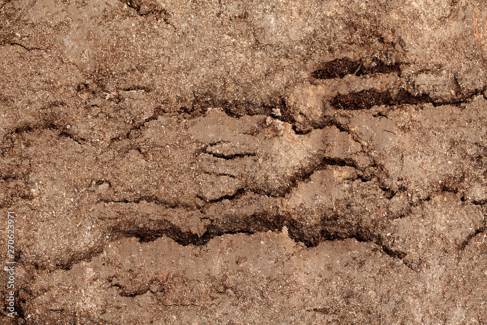 Dirty dry dark brown soil sand earth land ground. Natural environmental textured abstract background terrain. Unusual pattern shape with cracks, holes and curvy lines.