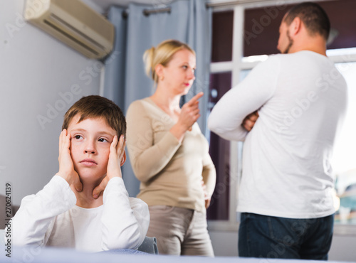 unhappy boy at home while parents quarreling