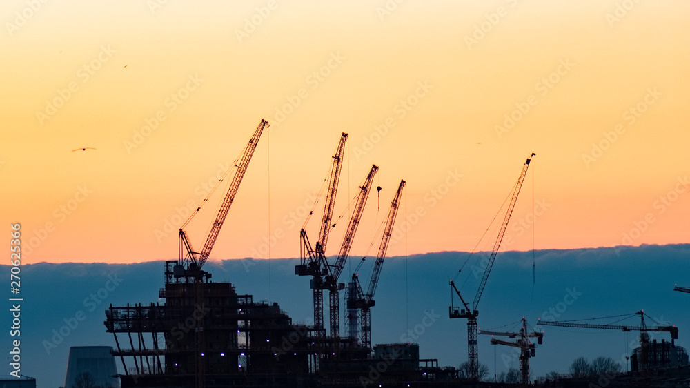 construction cranes at sunset