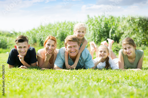 Glad man and woman with four kids lying in park