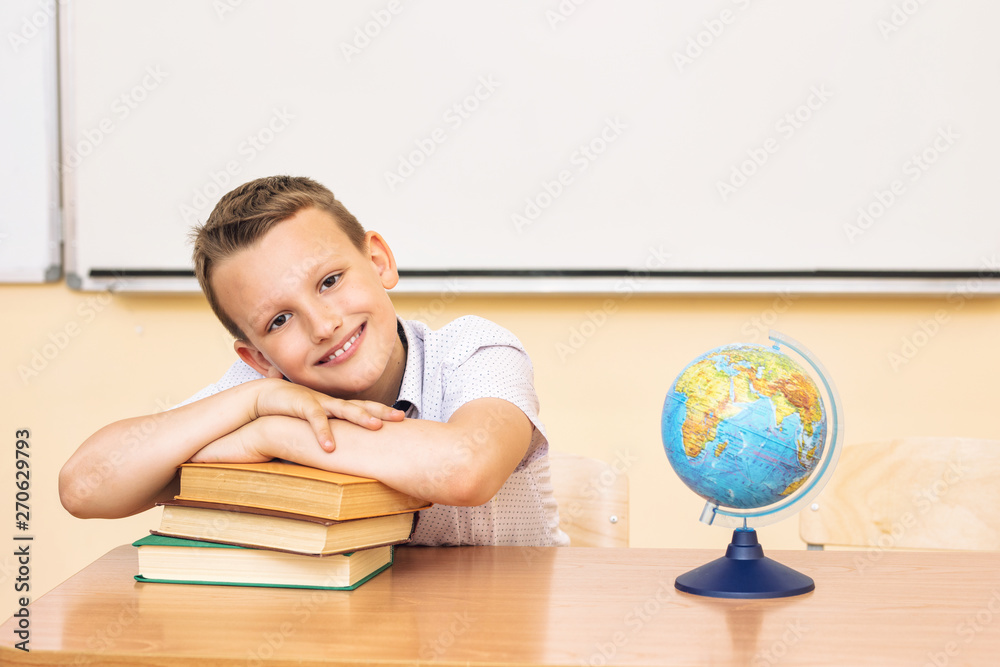 Boy child schoolboy happy, funny and cute with smile - portrait in classroom sitting at Desk - obrazy, fototapety, plakaty 