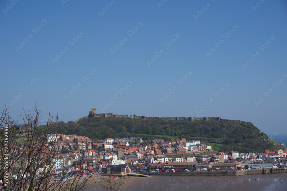 View of castle on hill above town in Scarborough, UK on a clear blue sky sunny day