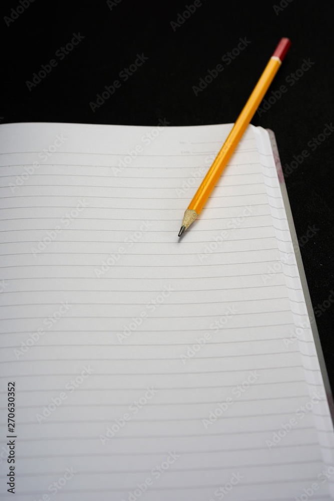 image of a notebooks and pencil on black background, close-up, selective focus image of a notebooks and pencil on black background, close-up, selective focus