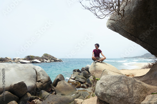 Male traveler sitting on the rock at the coast photo