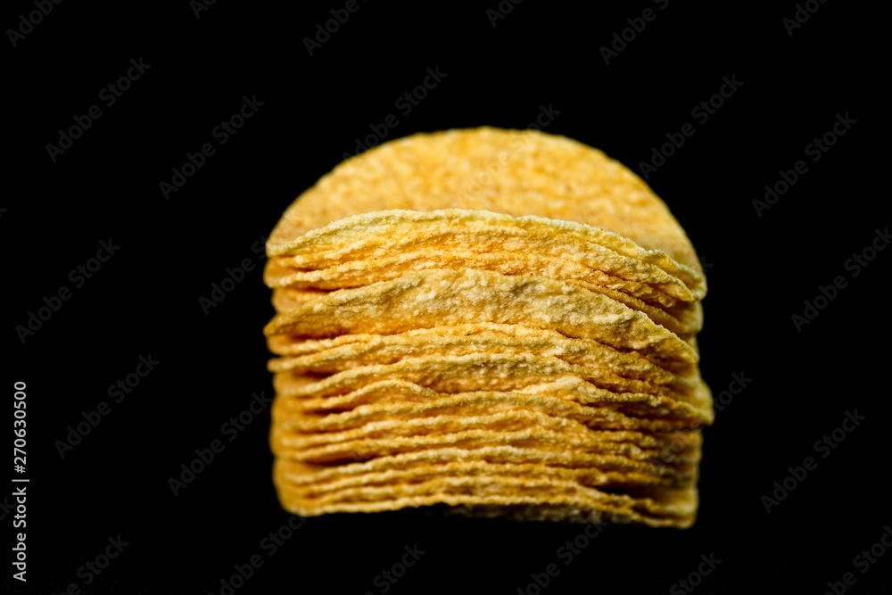 Delicious and crisp potato chips, isolated against black background, selective focus Delicious and crisp potato chips, isolated against black background, selective focus