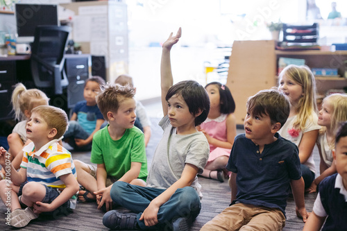 Kindergarten kid raising hand in classroom photo