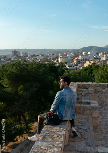 Young man with cap and jacket is looking the city