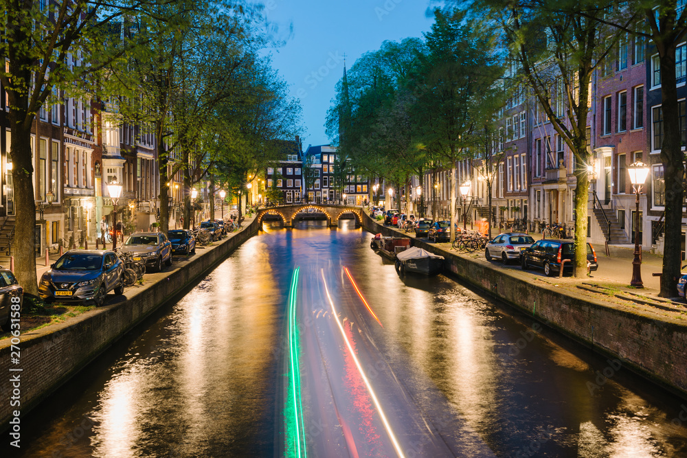 Amsterdam, Netherlands - light trails of a boat and night view on a canal