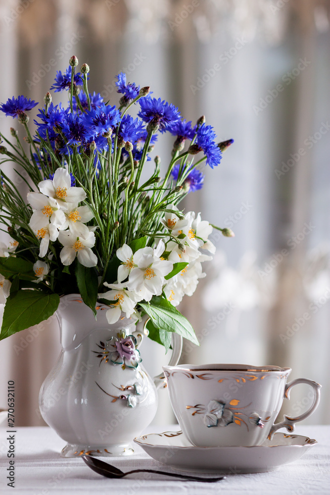 On the table is a cup of tea and a bouquet of wild flowers in a vase On the table is a cup of tea and a bouquet of wild flowers in a vase