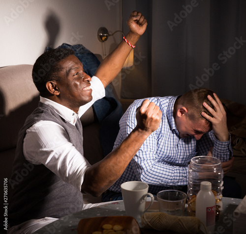 Male friends watching football match on tv  and having fun photo