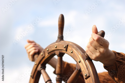 Steering hand wheel ship on sky background, hand hold hand wheel