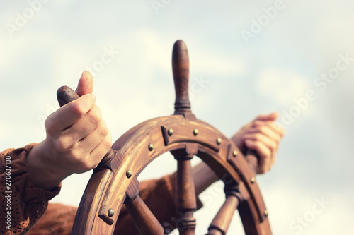 Fényképezés Steering hand wheel ship on sky background, hand hold hand wheel