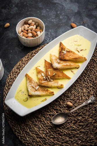 shahi tukra/tukda or Double ka meetha is a bread pudding Indian sweet of fried bread slices soaked in rabid or sweet saffron milk garnished with dry fruits, selective focus photo