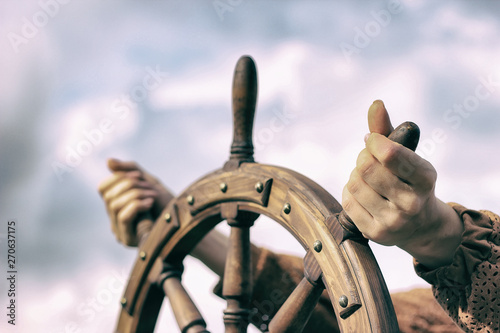 Steering hand wheel ship on sky background, hand hold hand wheel