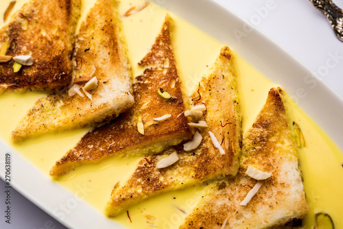 shahi tukra/tukda or Double ka meetha is a bread pudding Indian sweet of fried bread slices soaked in rabid or sweet saffron milk garnished with dry fruits, selective focus photo