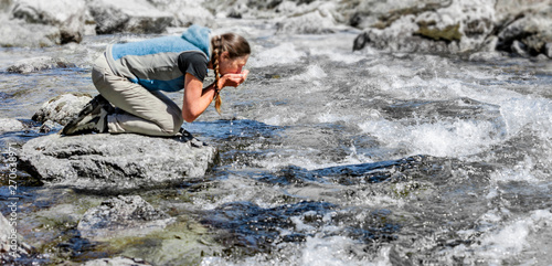 Frau beim Wasser trinken aus einem Bergbach