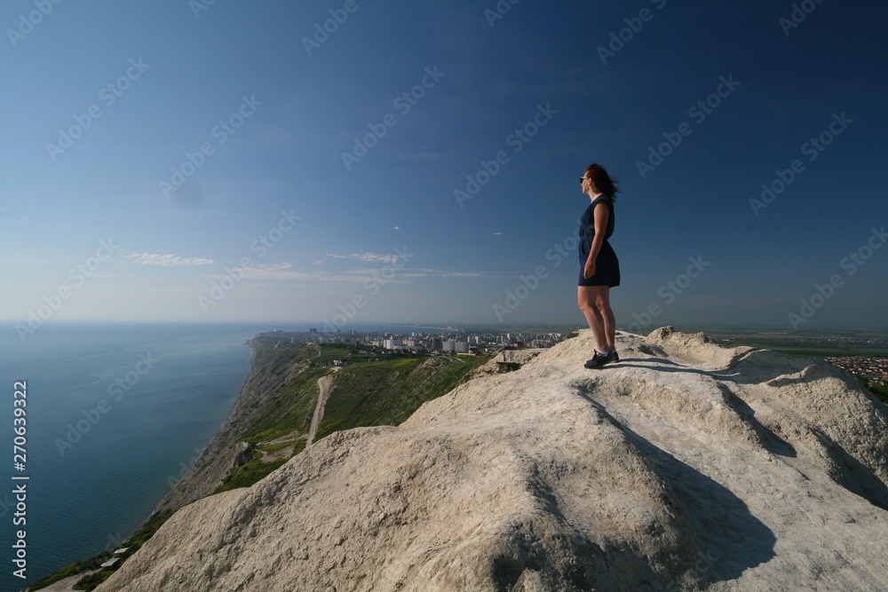 A young woman on a mountain top admires the view of the Black sea, Anapa, Russia.