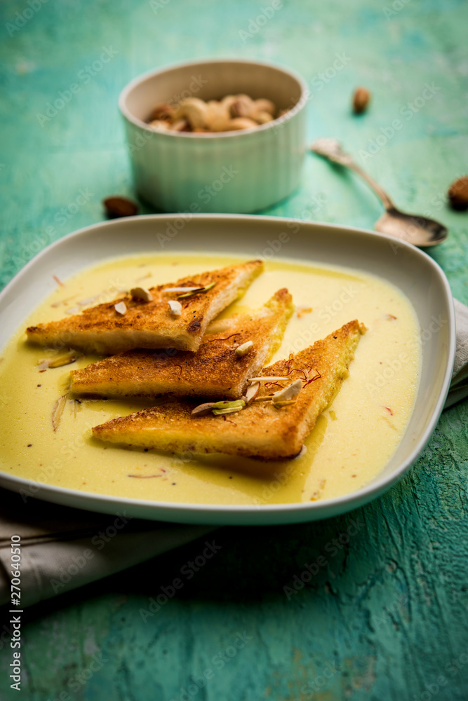 shahi tukra/tukda or Double ka meetha is a bread pudding Indian sweet of fried bread slices soaked in rabid or sweet saffron milk garnished with dry fruits, selective focus shahi tukra/tukda or Double ka meetha is a bread pudding Indian sweet of fried bread slices soaked in rabid or sweet saffron milk garnished with dry fruits, selective focus